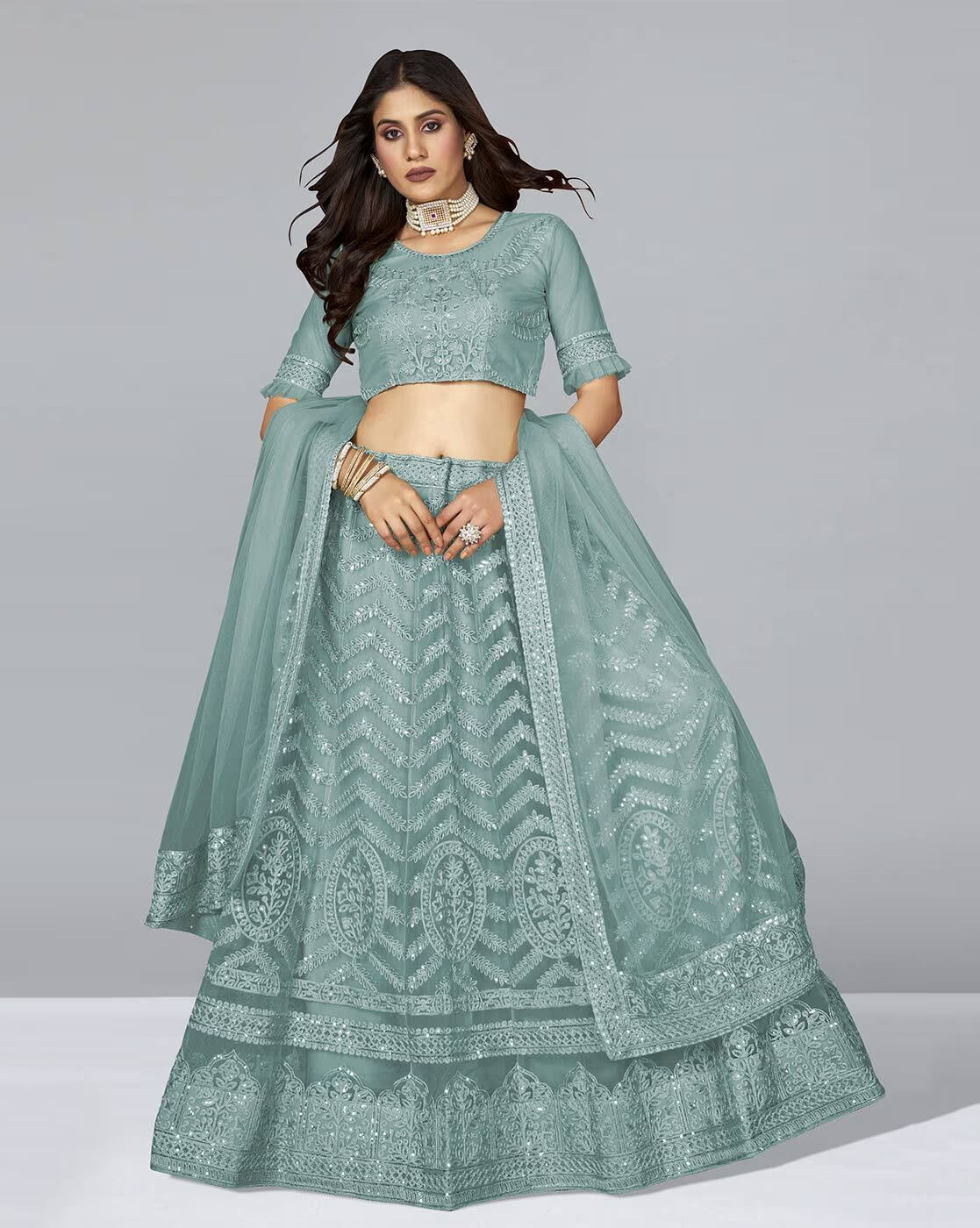 Model wearing mint green Embellished A-Line Lehenga Choli Set with embroidered skirt sheer dupatta and choker