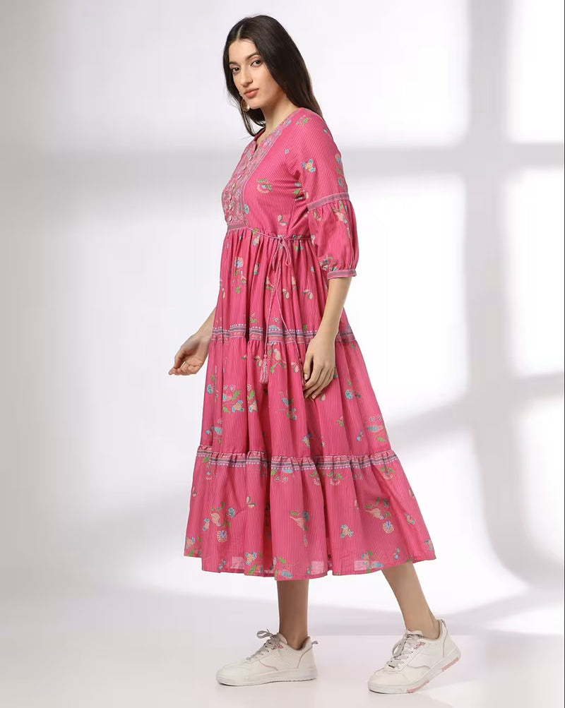 Aromie pink floral print tiered dress worn by a woman with half sleeves and midi length
