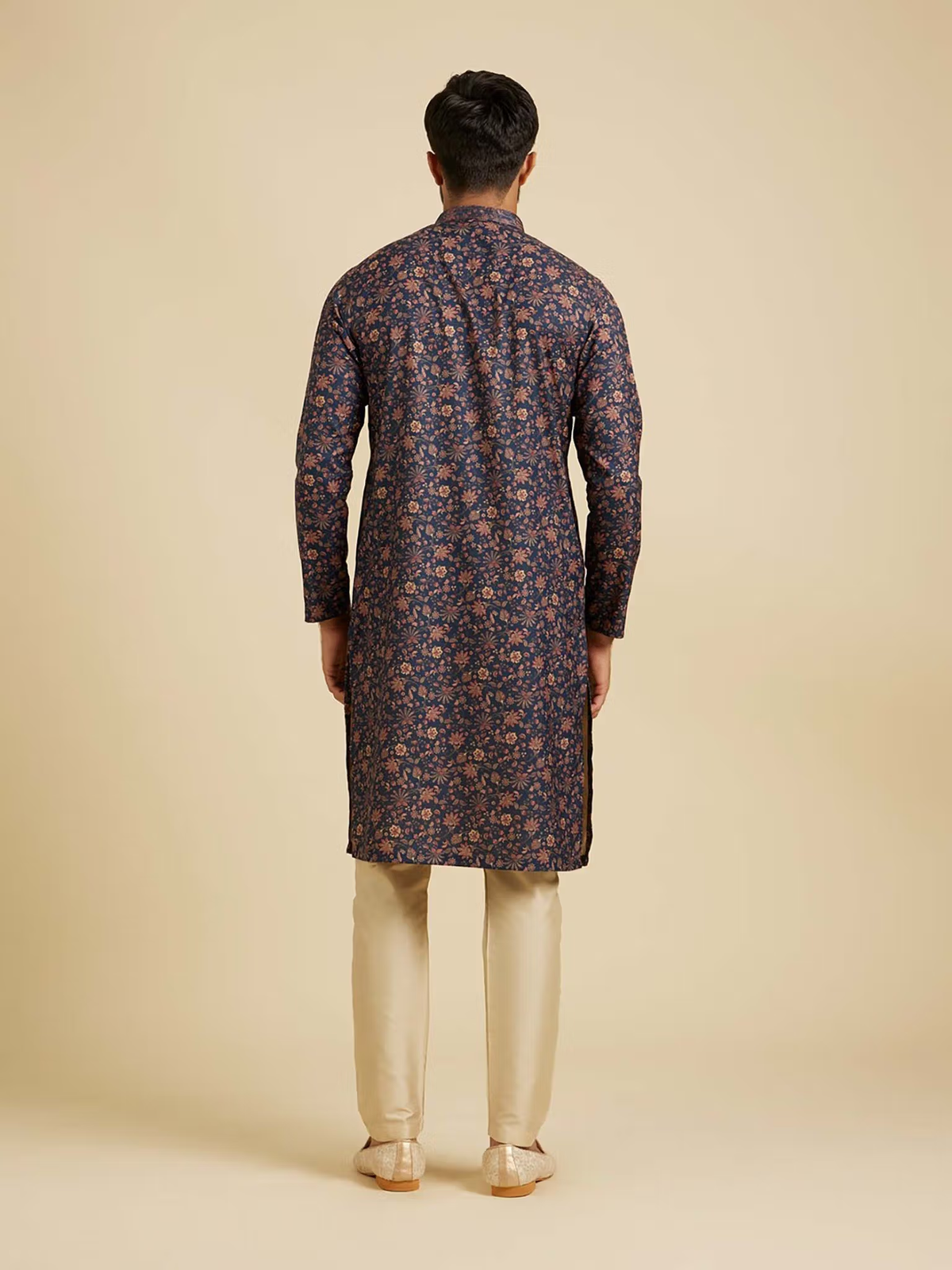 Rear view of man wearing AROMIE blue floral kurta pyjama set with beige trousers on neutral background