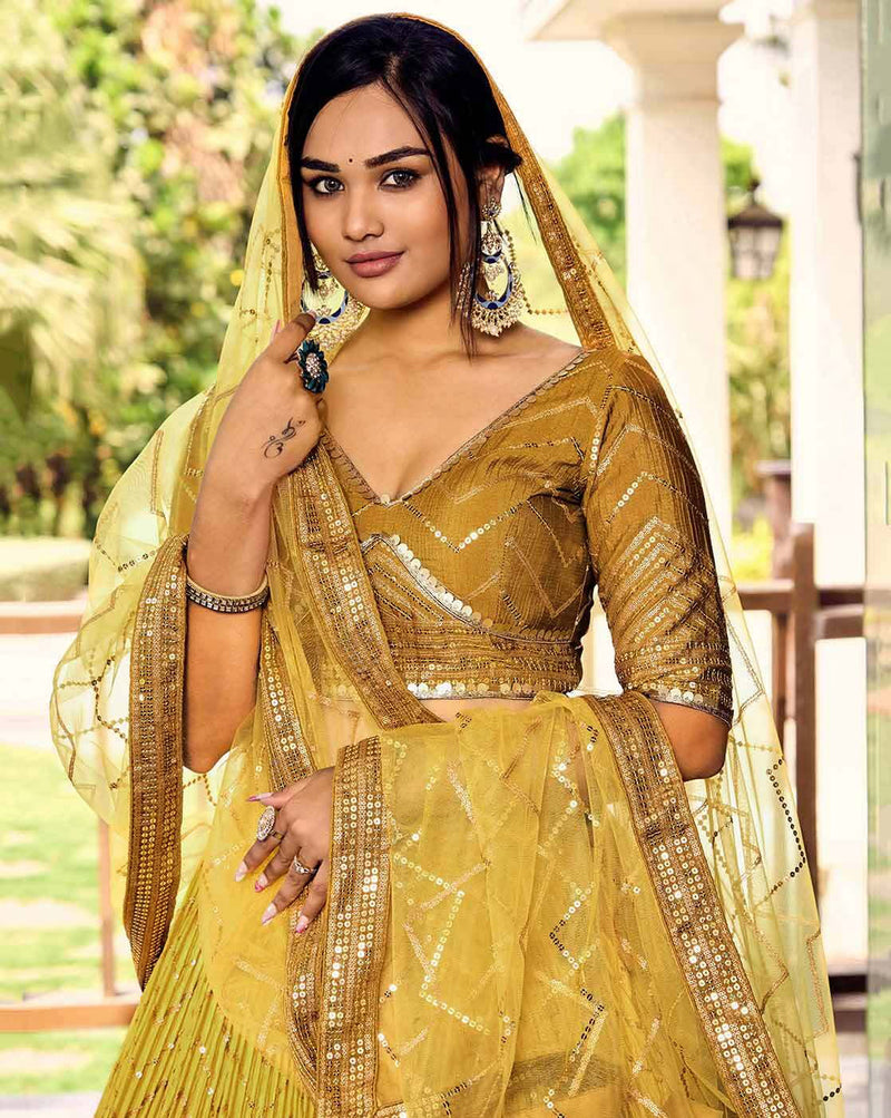 Model wearing mustard yellow embellished flared lehenga choli Canada with sequin work dupatta and heavy earrings