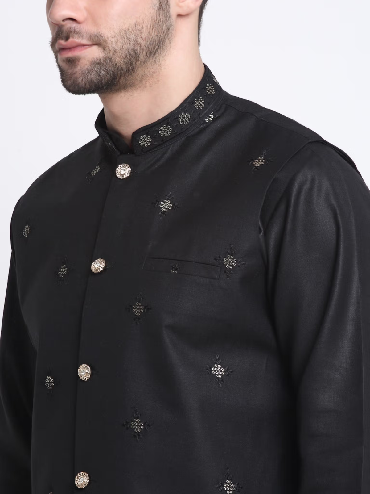 Close up of male model wearing men's black kurta pajama nehru jacket set with embroidered motifs and gold buttons