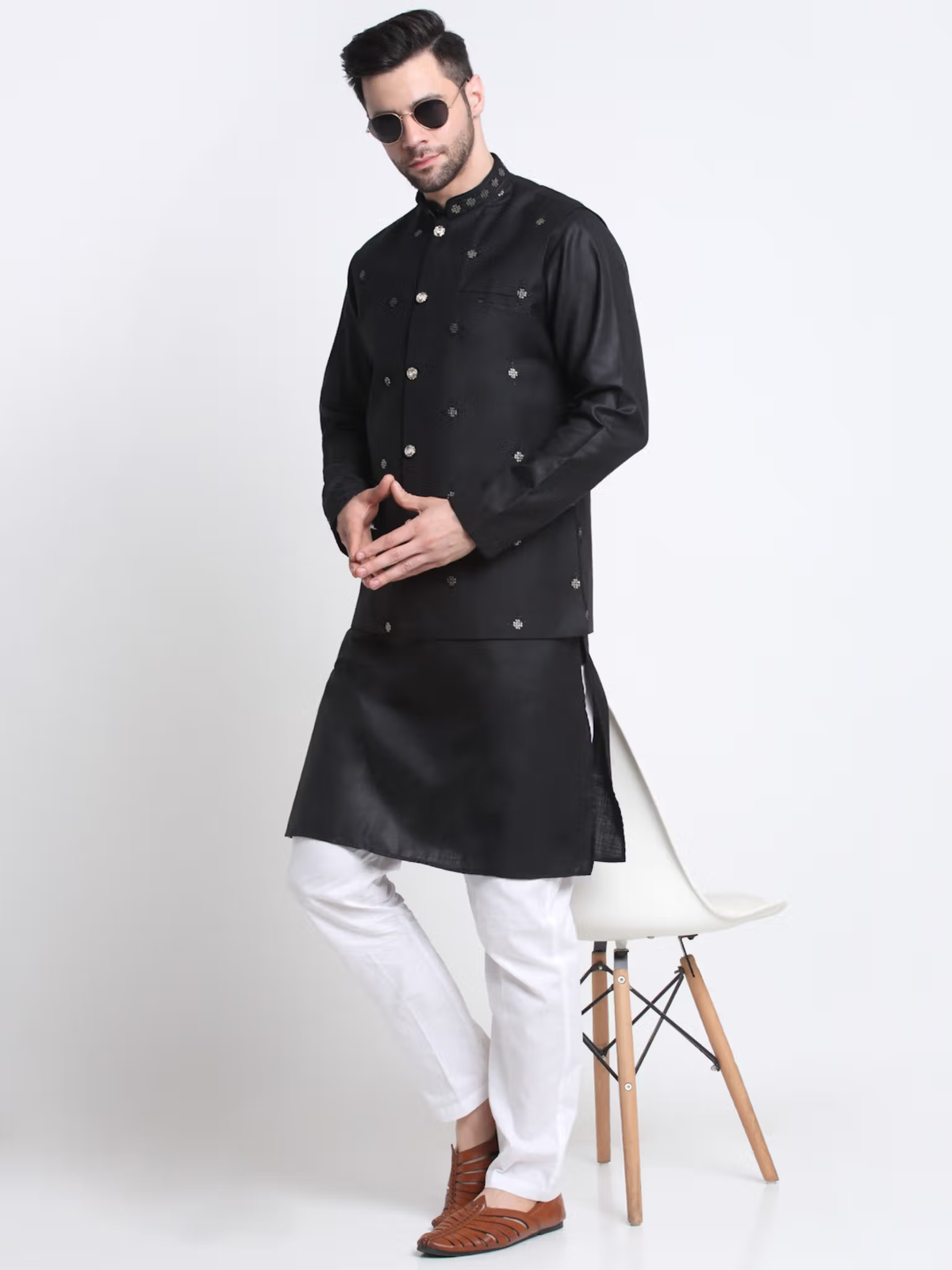 Model wearing men's black kurta pajama nehru jacket set with white pajama pants brown shoes and sunglasses
