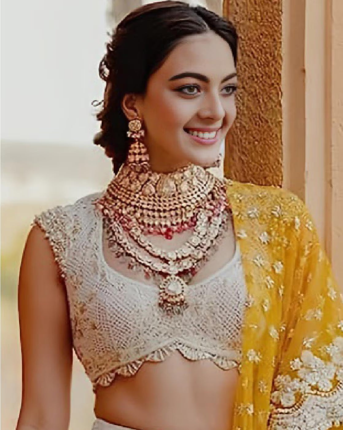 Smiling model in cream embroidered choli with yellow embellished dupatta and layered jewelry women embellished lehenga choli set