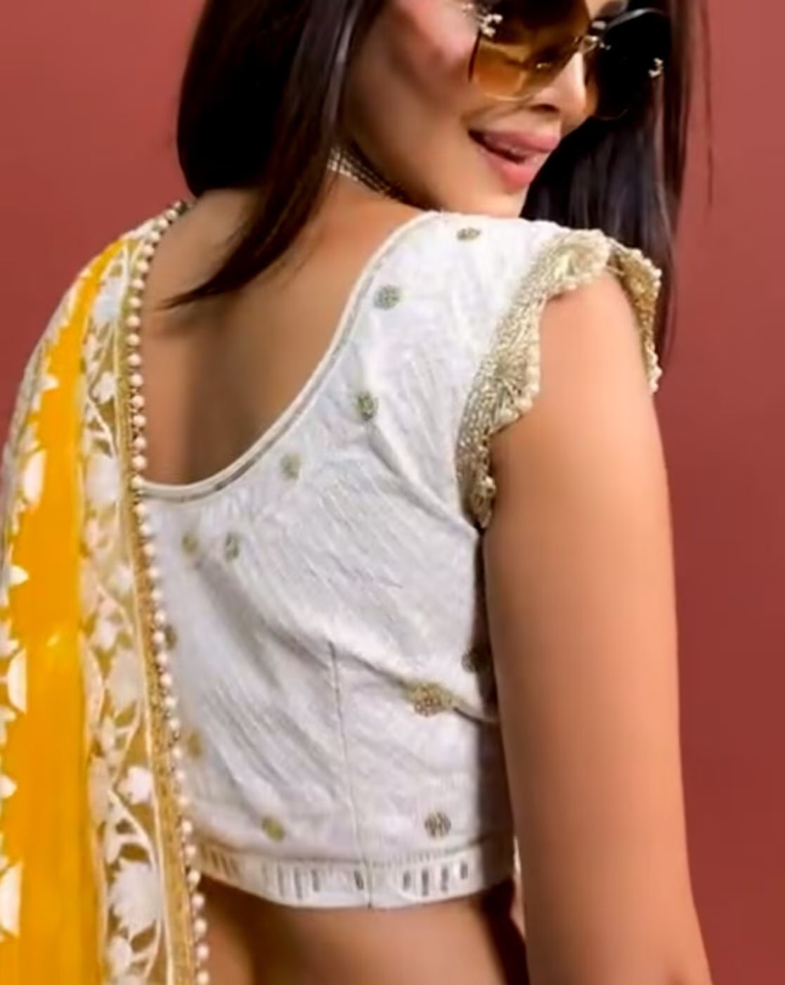 Model wearing women embellished lehenga choli set white embroidered blouse with gold trim and yellow dupatta