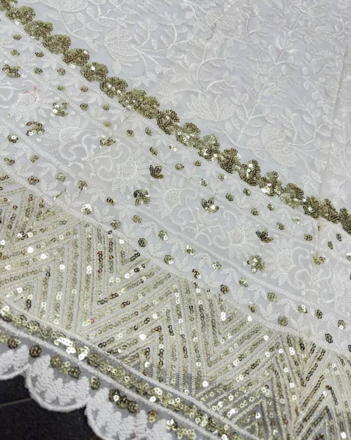 White and gold embroidered fabric closeup of women embellished lehenga choli set with sequin border