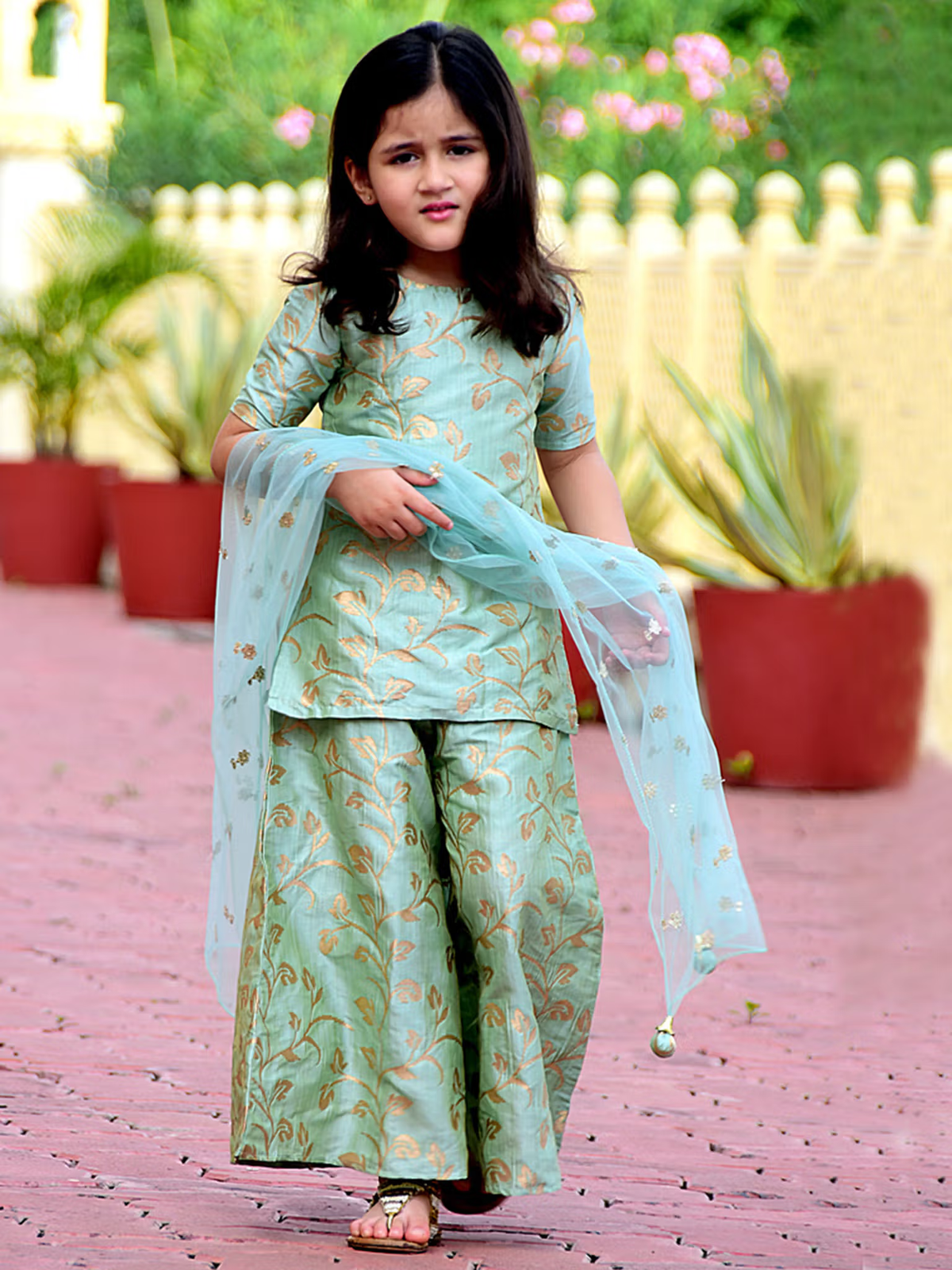 Young girl modeling green leaf printed kurta palazzo dupatta set in mint green with gold leaf motifs