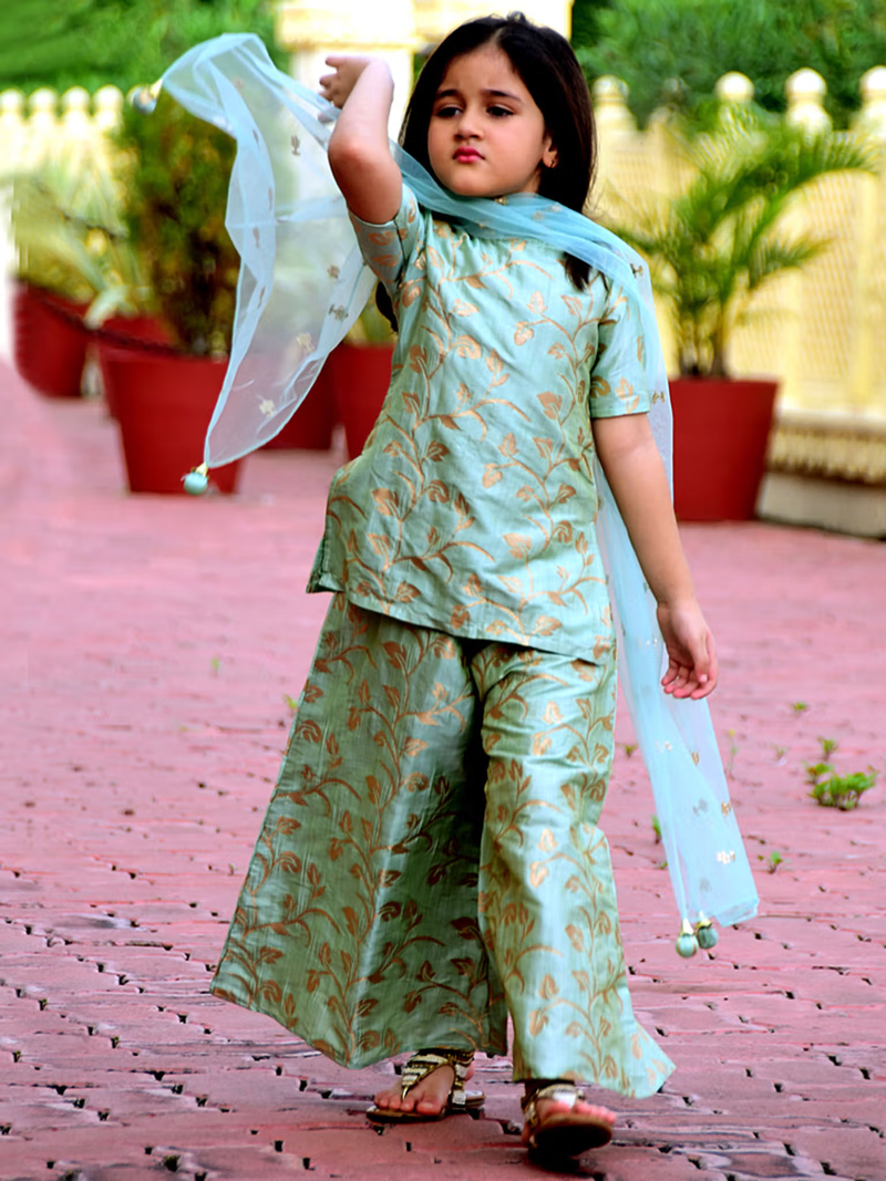 Young girl modeling green leaf printed kurta palazzo dupatta set in mint green with gold leaf motif outdoor walk