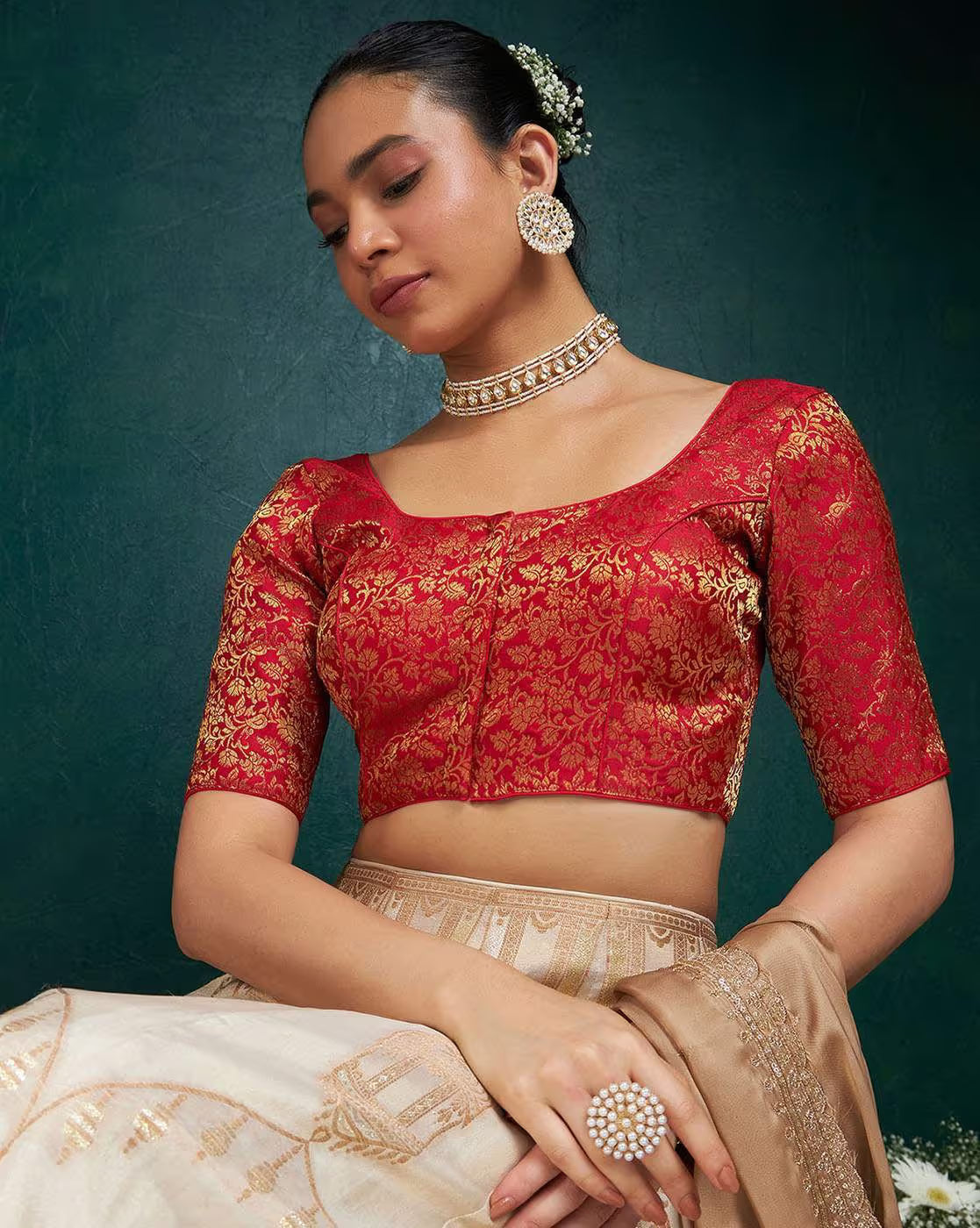 Woman wearing a red and gold traditional outfit with jewelry against a dark green background