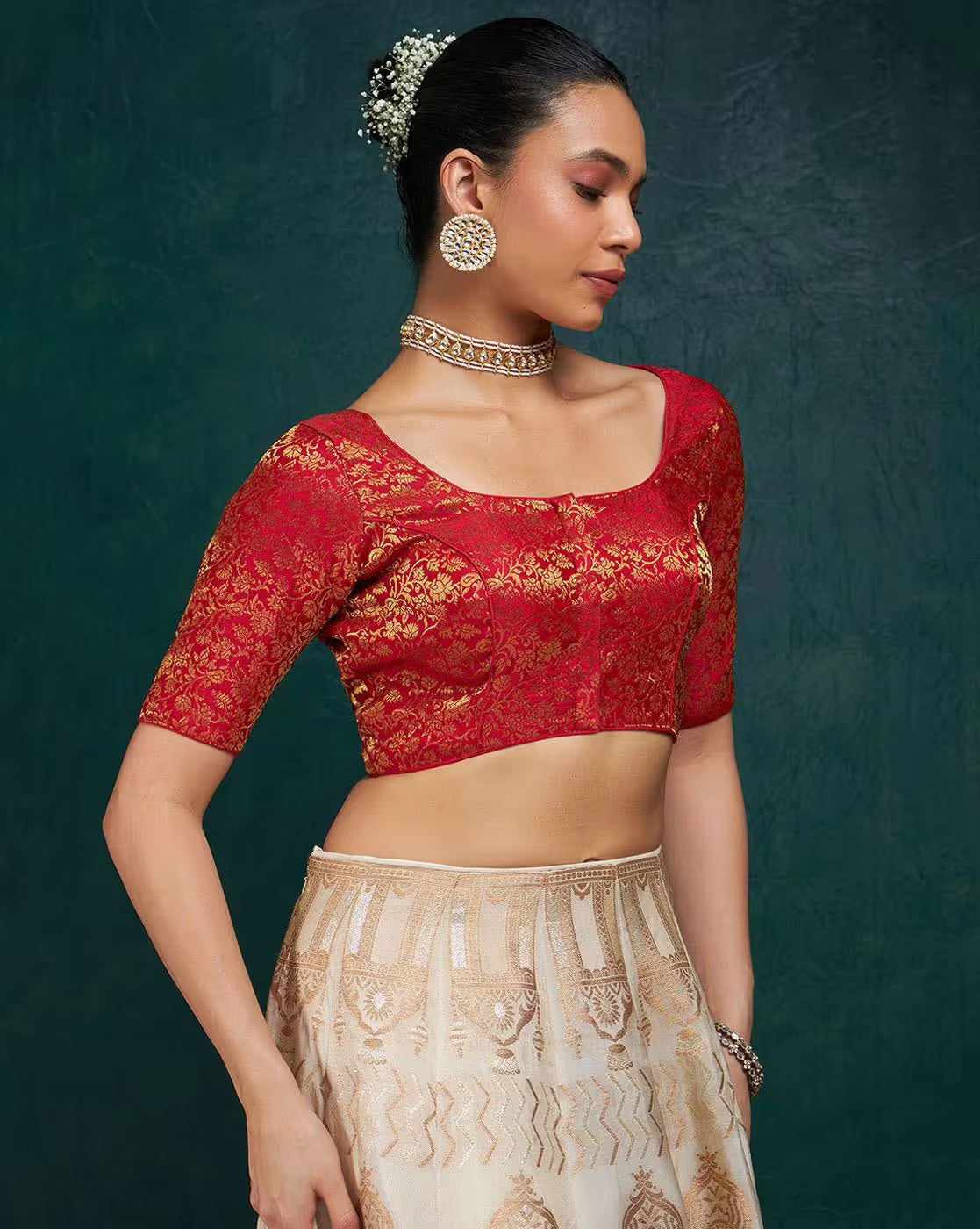 Woman wearing a red blouse with gold patterns and a beige skirt against a dark green background