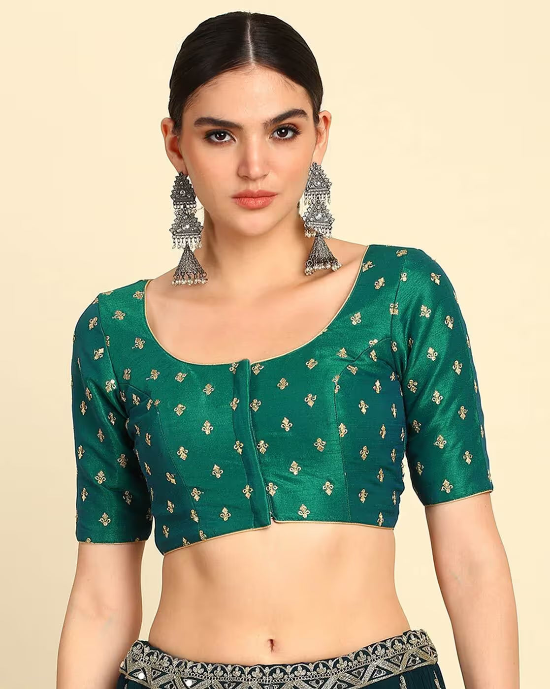 Woman wearing a green blouse with gold patterns on a beige background