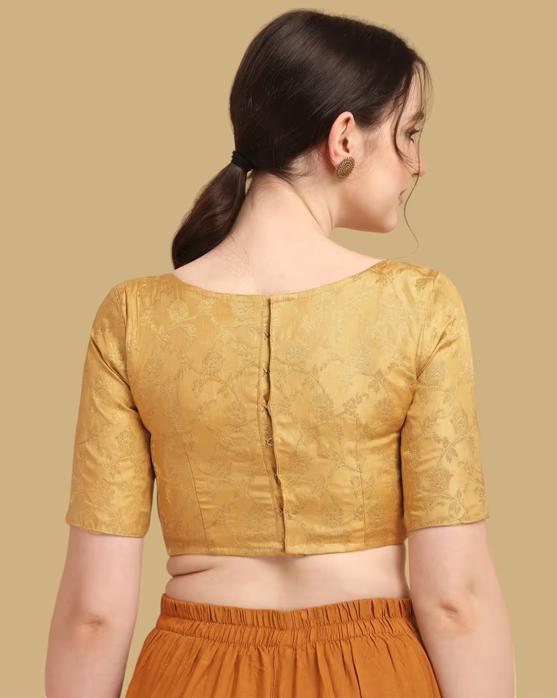 Woman wearing a mustard yellow blouse with a beige background