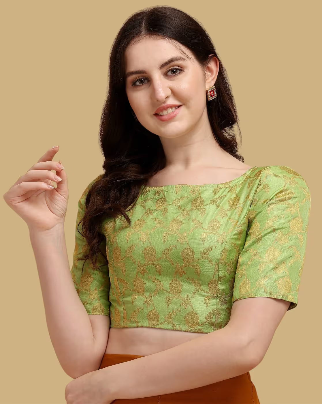 Woman wearing a green blouse with gold patterns on a beige background