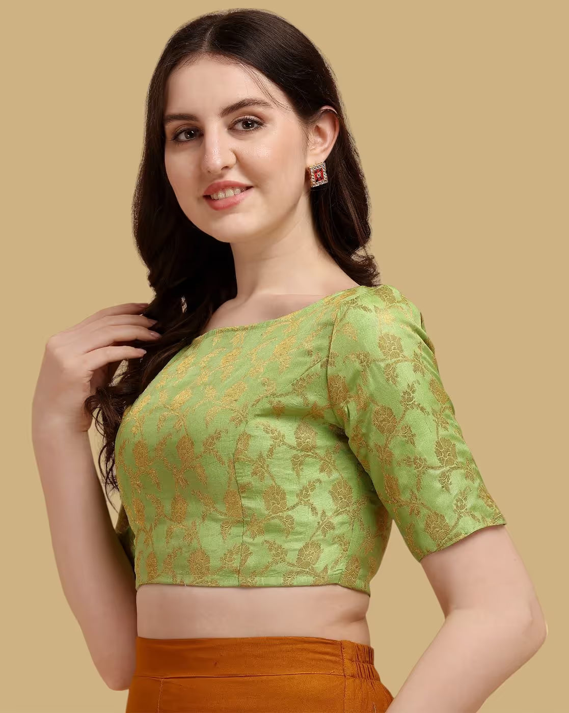 Woman wearing a green blouse with gold patterns on a beige background