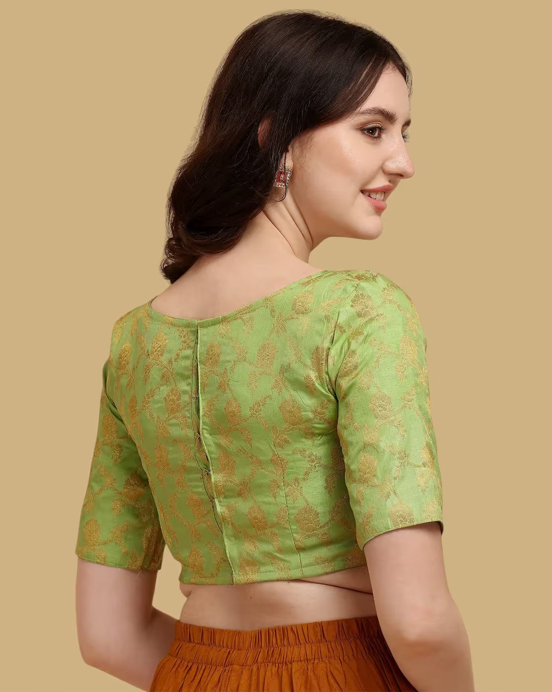 Woman wearing a green blouse with gold patterns on a beige background