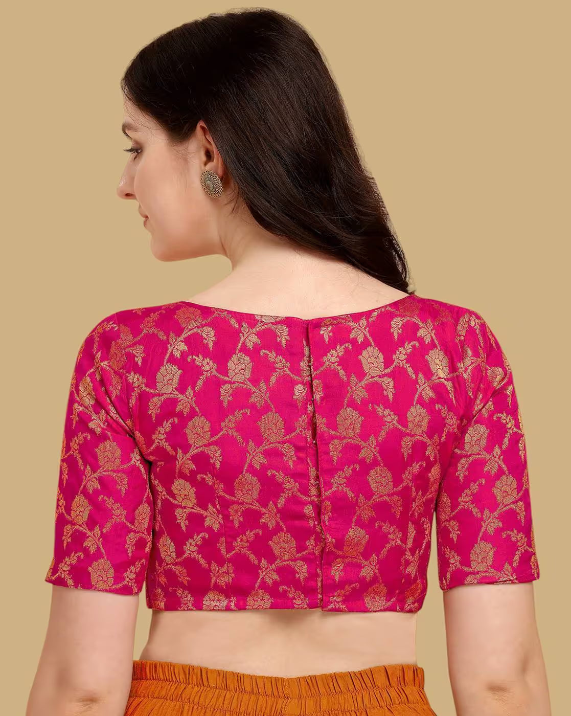 Woman wearing a pink blouse with gold floral patterns on a beige background
