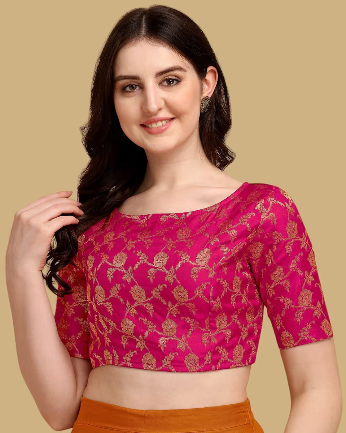 Woman wearing a pink blouse with gold patterns on a beige background