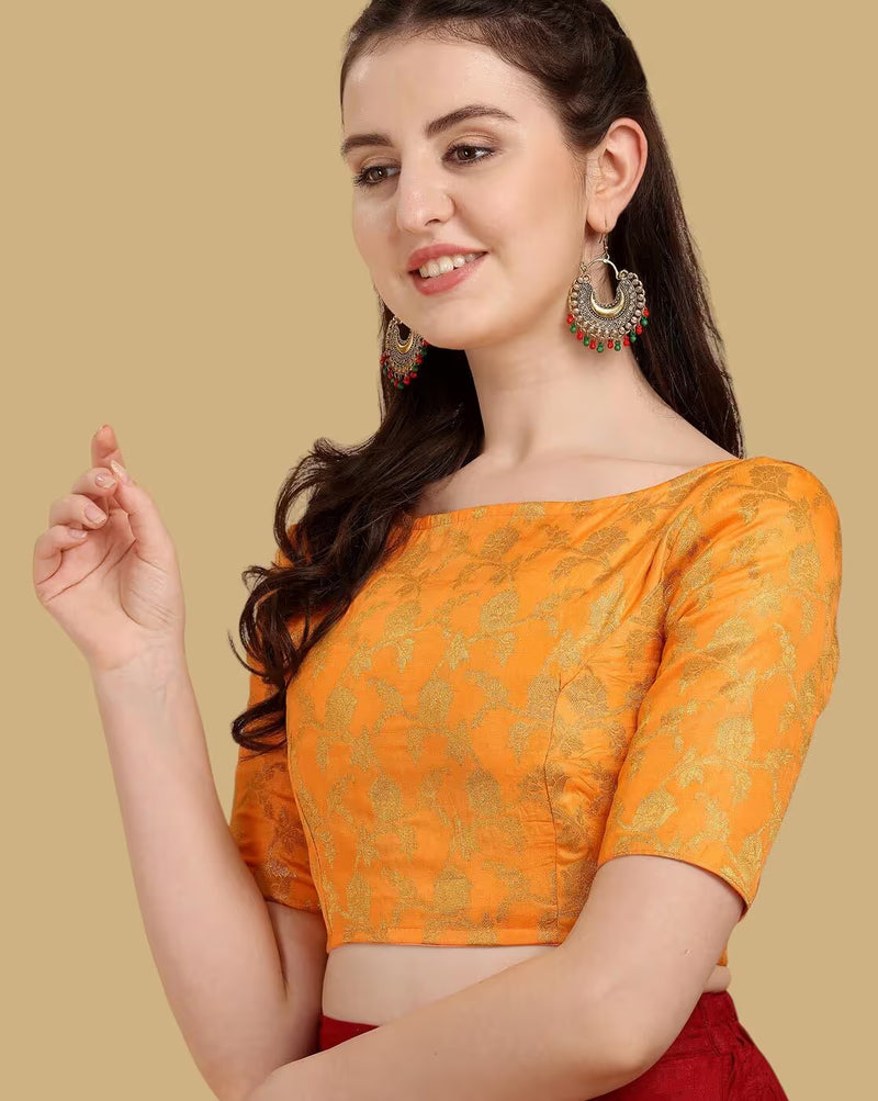 Woman wearing an orange blouse with gold patterns on a beige background