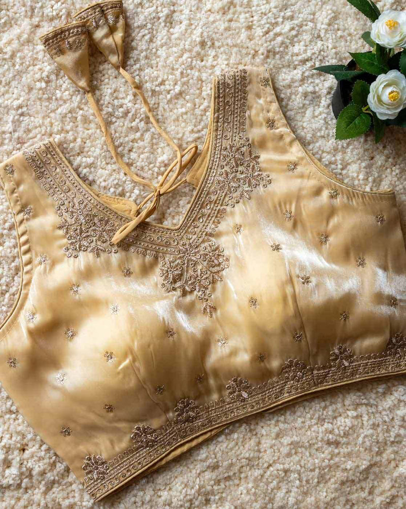 Gold embroidered blouse on a textured surface with flowers in the background