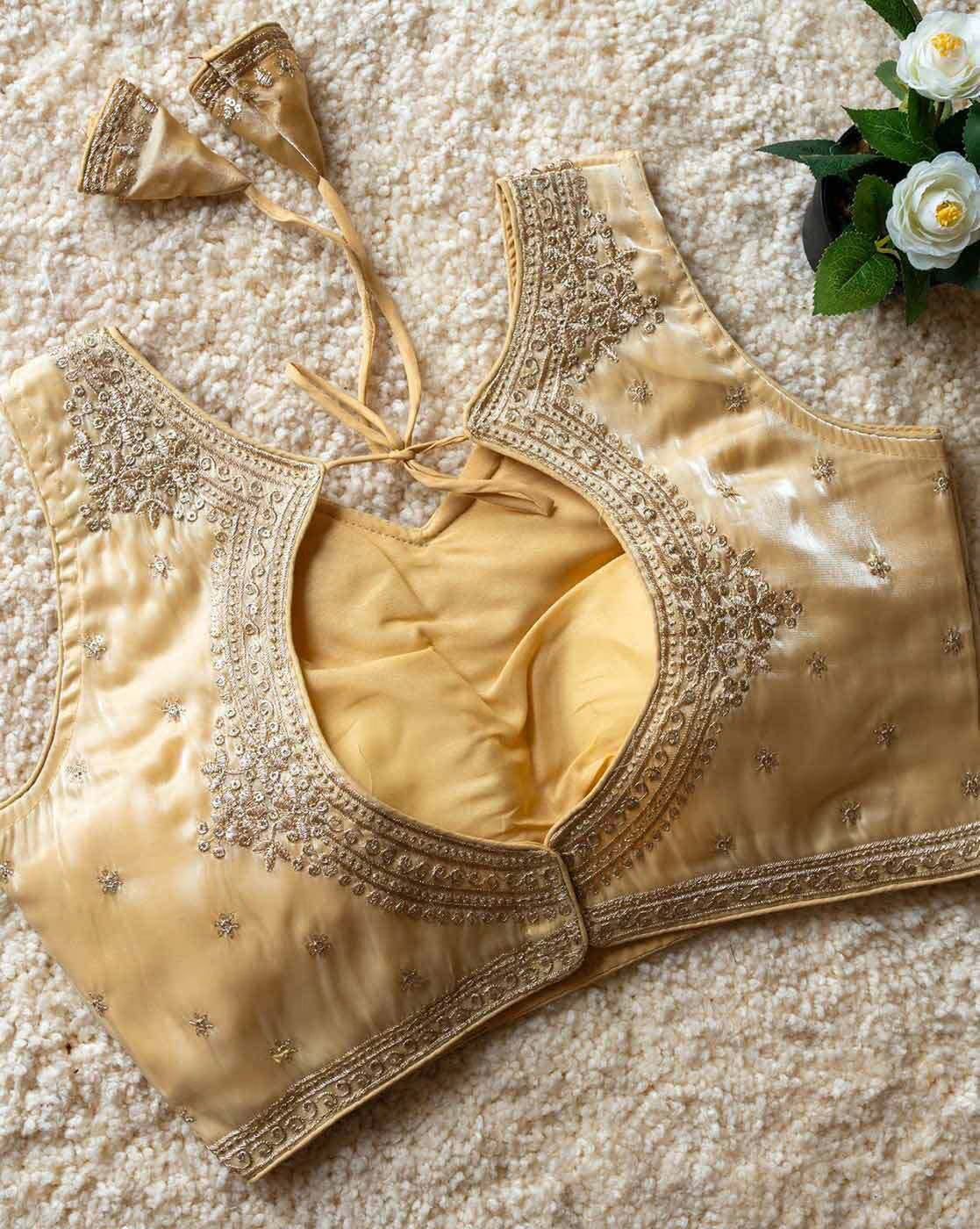 Gold embroidered blouse on a textured surface with flowers in the background