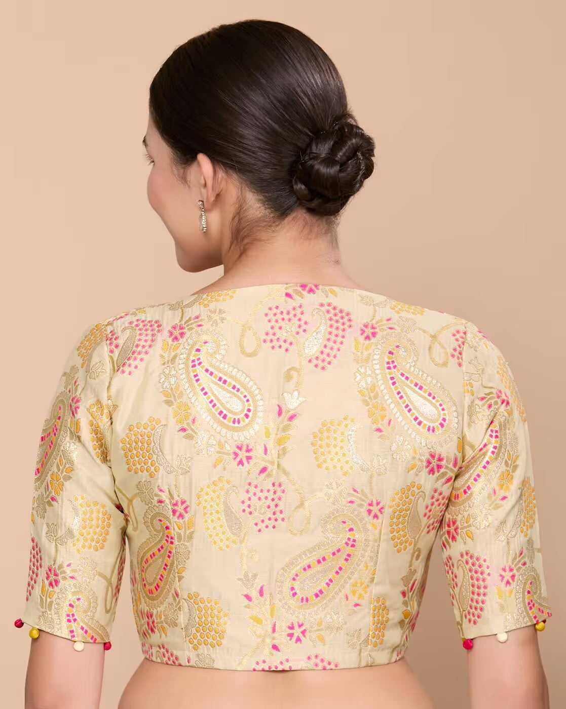 Woman wearing a beige blouse with pink and yellow floral patterns on a beige background