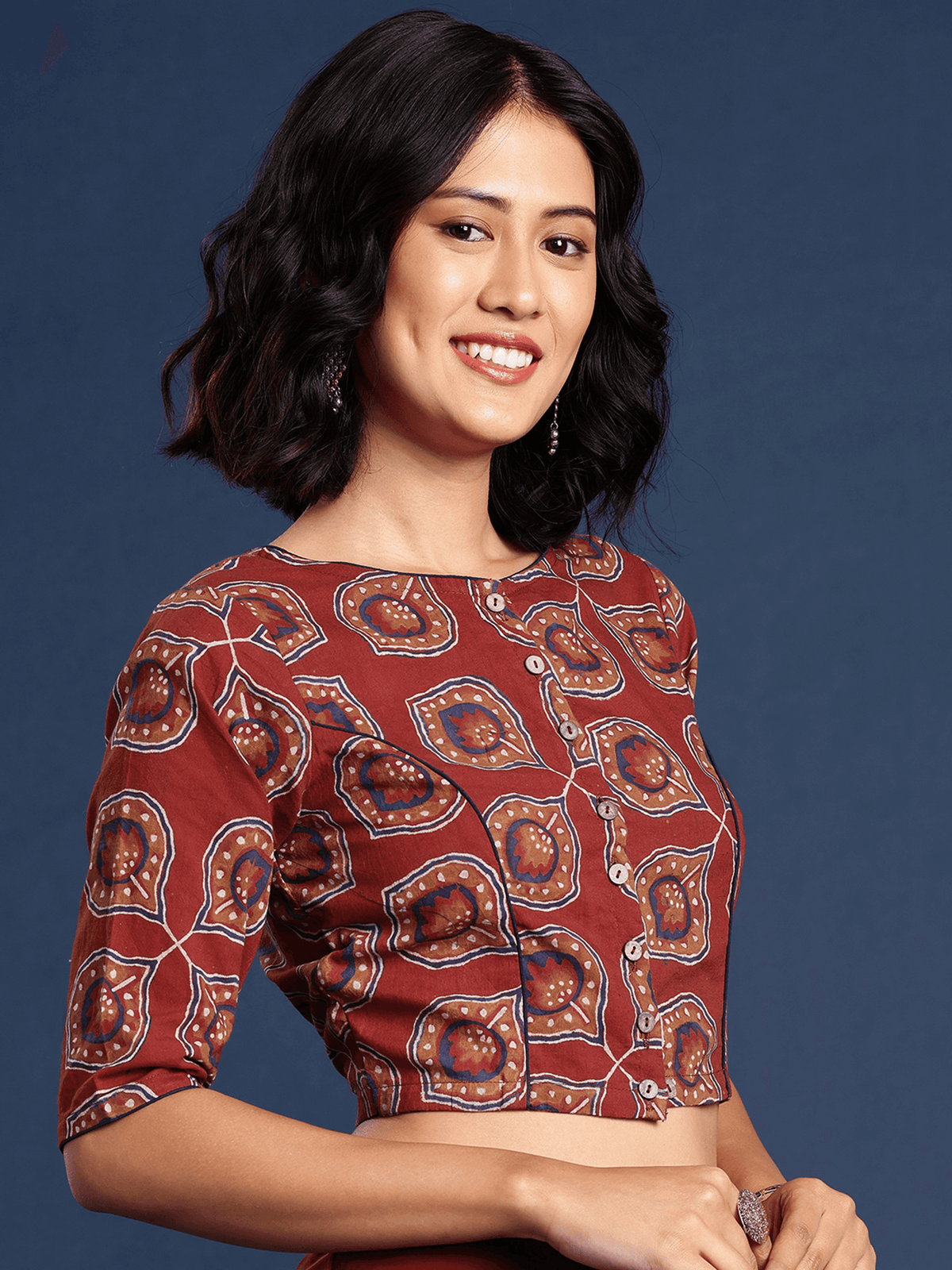 Woman wearing a patterned red top against a blue background