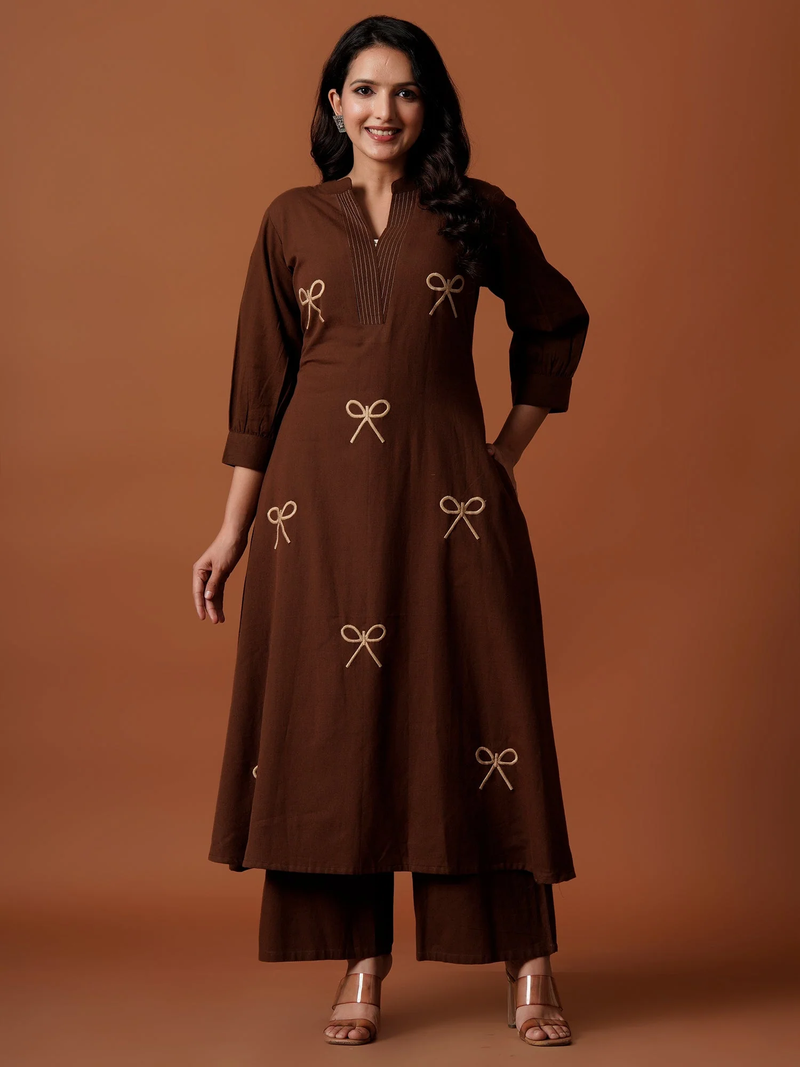 Woman wearing a brown dress with bow details on a brown background