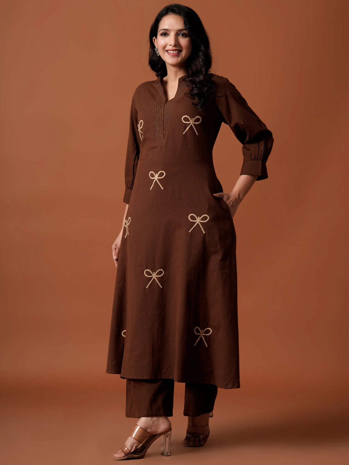 Woman wearing a brown outfit with bow patterns on a brown background
