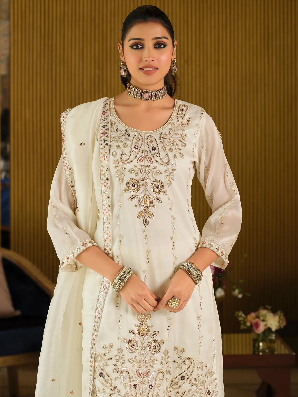 Woman wearing a white embroidered traditional outfit with gold details.