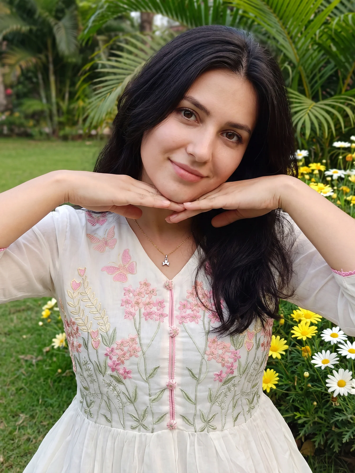 Woman in a floral dress posing outdoors with greenery and flowers in the background