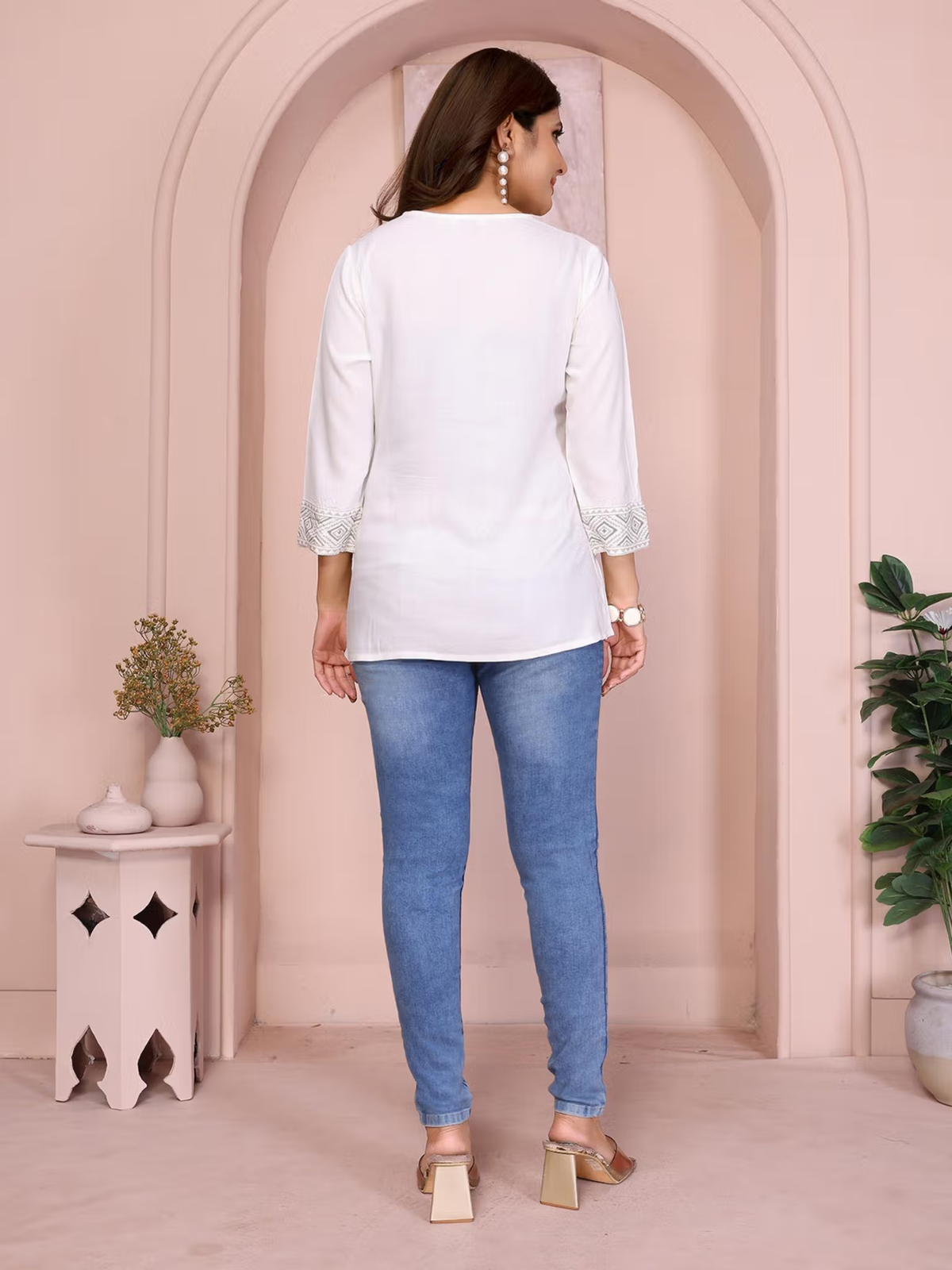 Back view of woman wearing aromie floral rayon suit set for women white kurti with embroidered cuffs and blue jeans