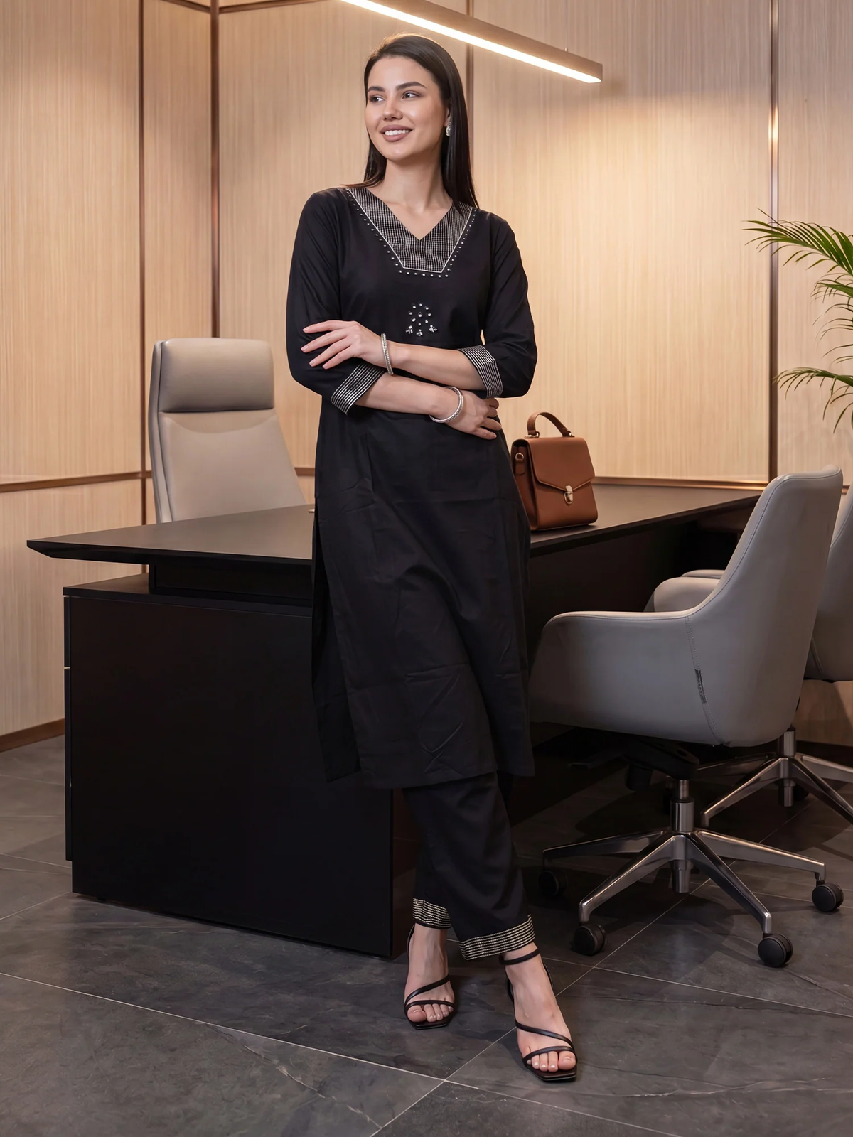 Woman in a black outfit standing in an office setting