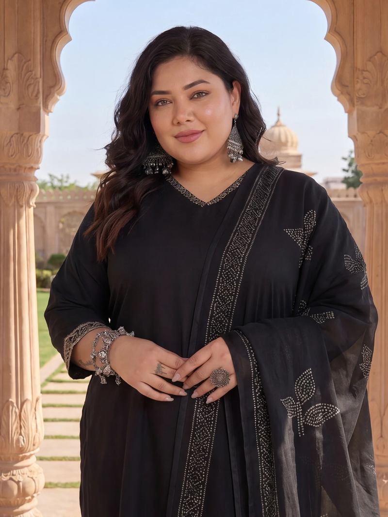 Woman in a black traditional outfit standing in front of an architectural structure with a blue sky.