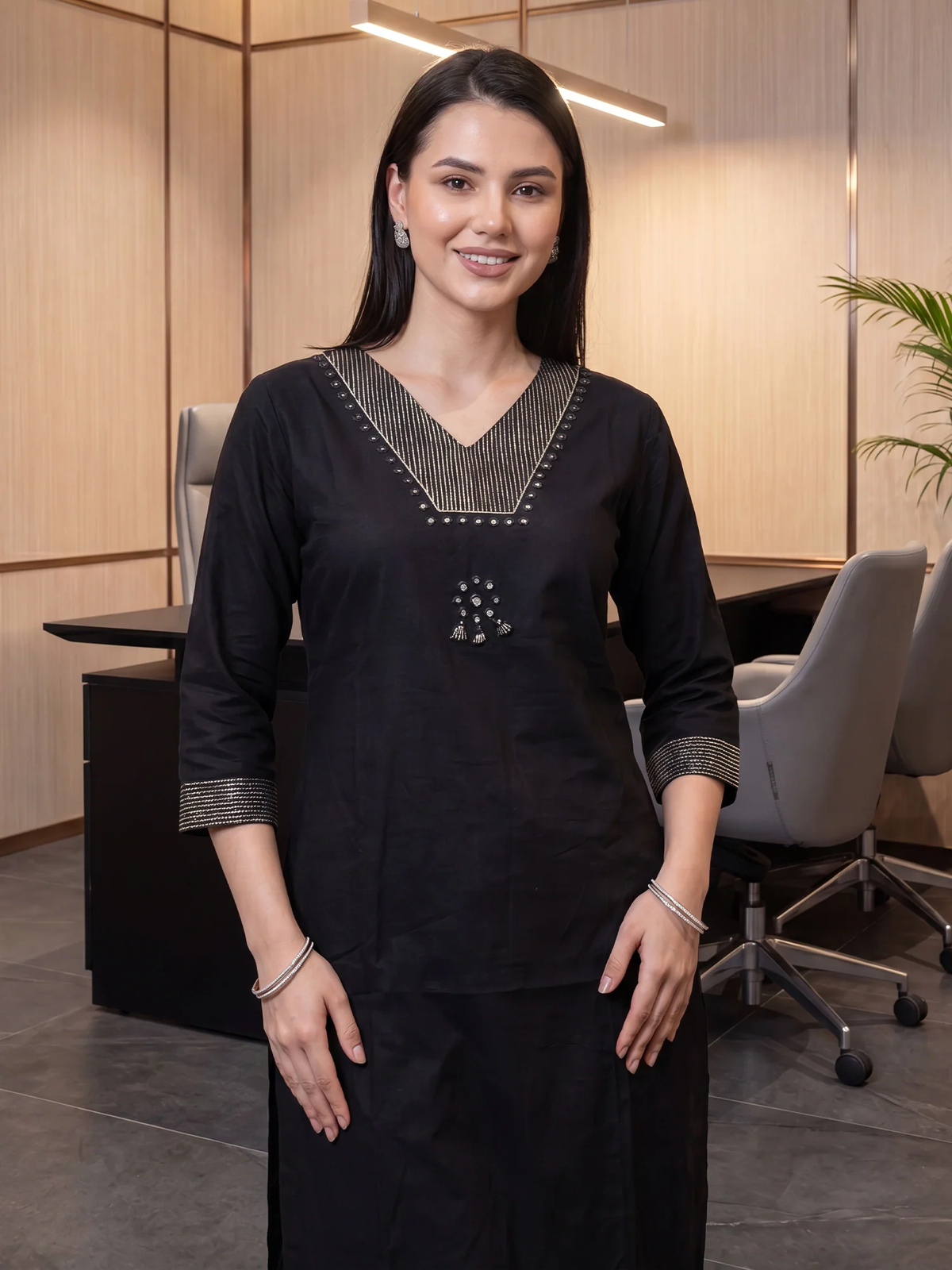 Woman in a black traditional outfit standing in an office setting