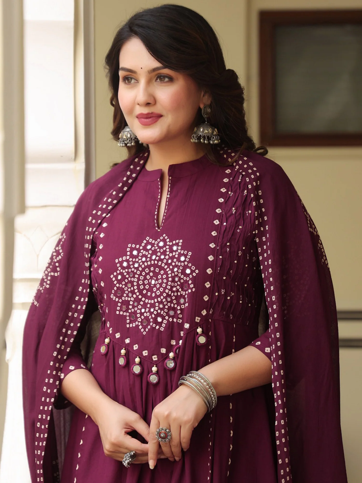 Woman wearing a purple traditional outfit with intricate designs indoors.