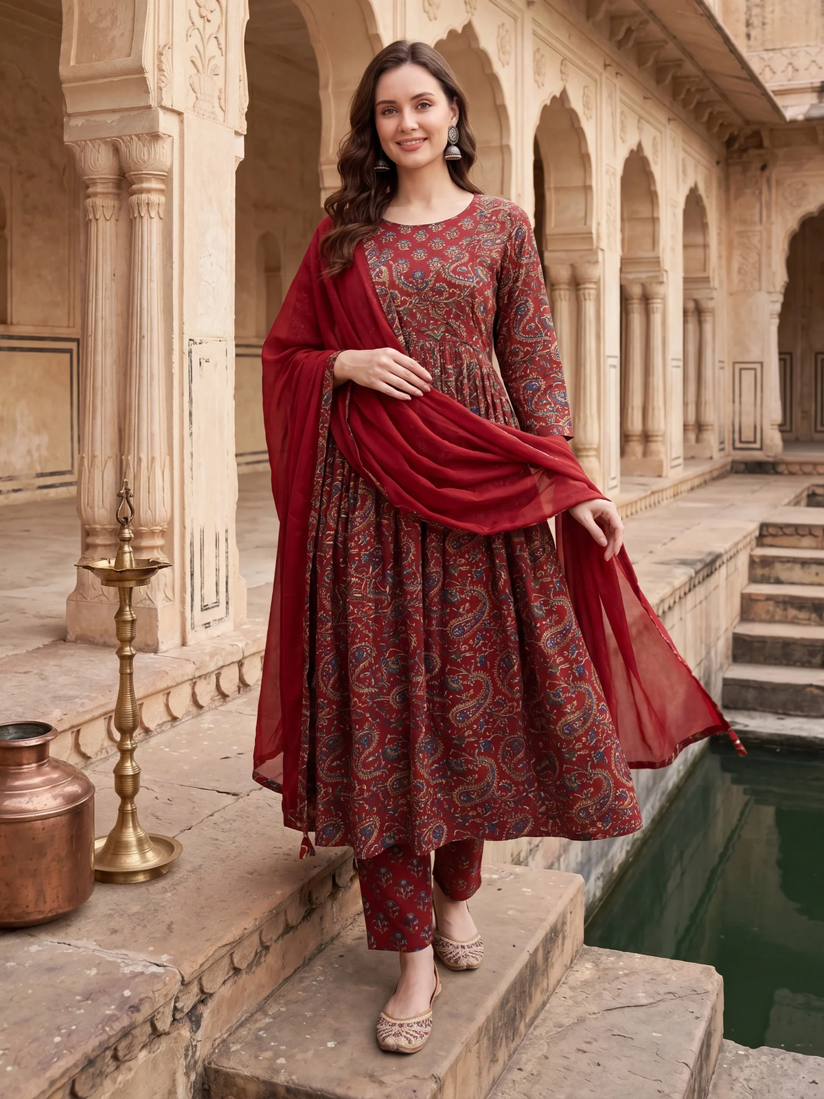 Woman in a red and patterned traditional outfit standing in an architectural setting.