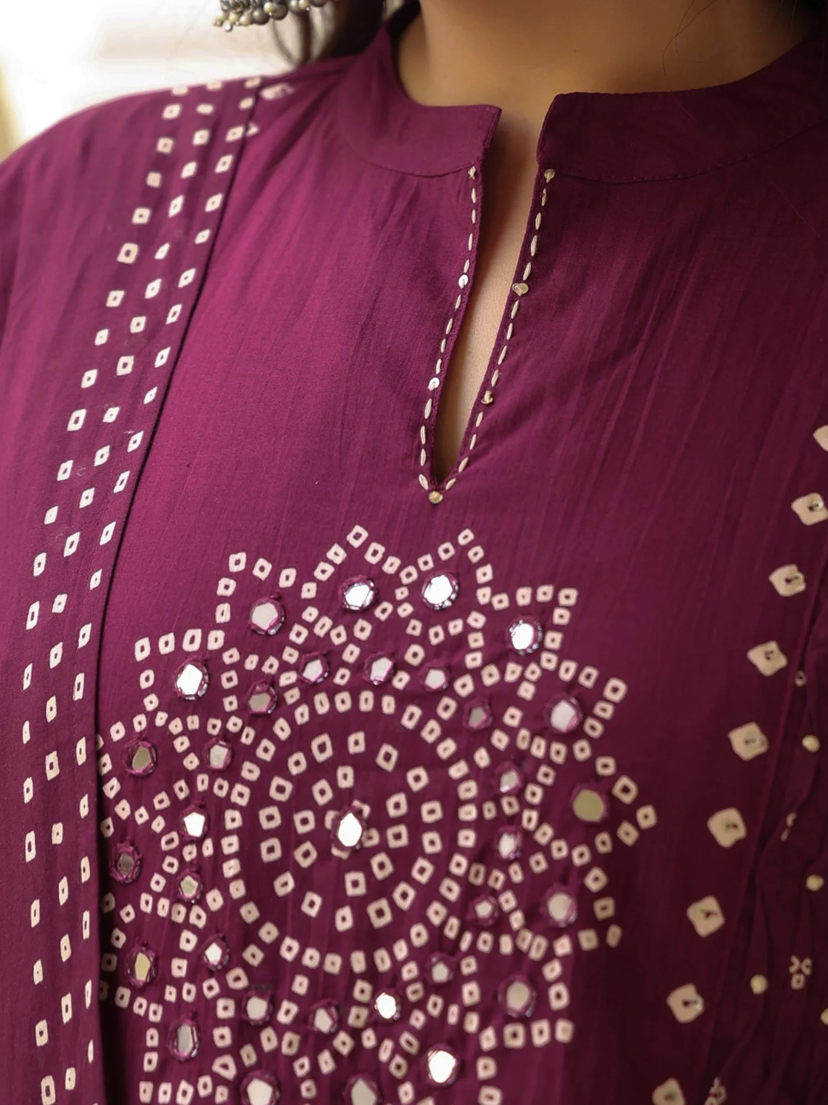 Close-up of a purple garment with intricate white embroidery