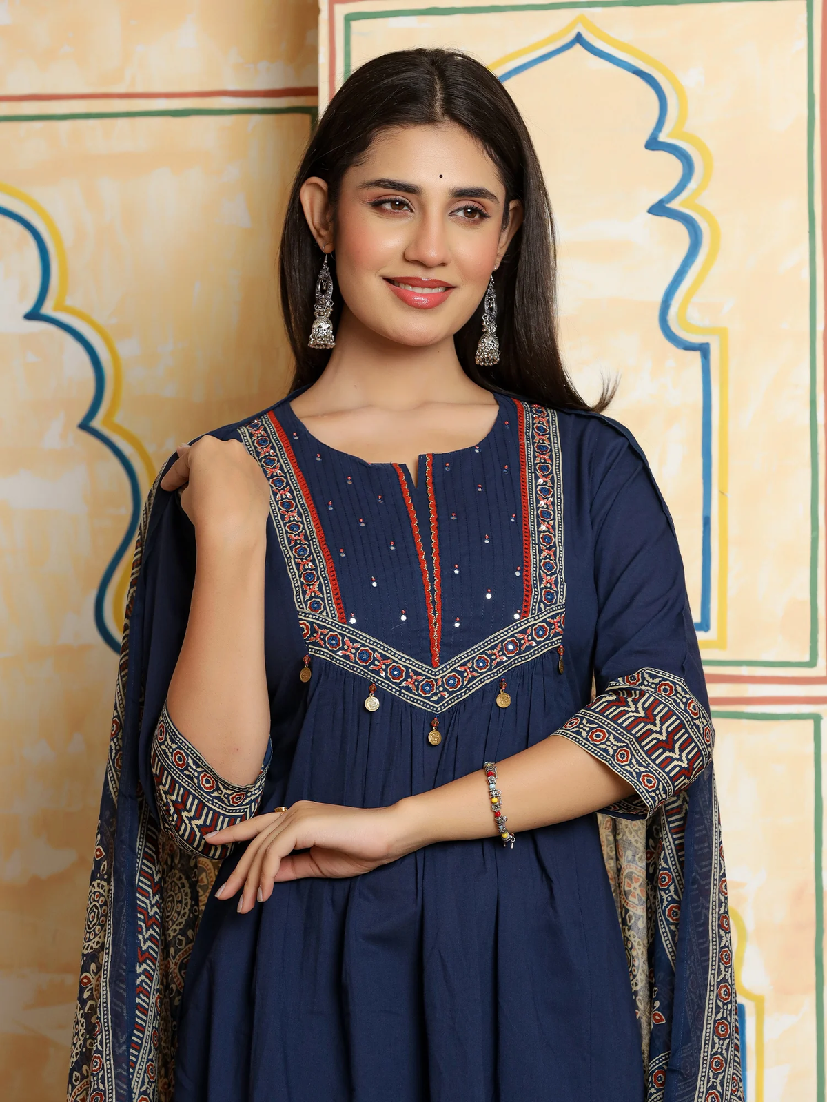 Woman wearing a blue embroidered dress with a decorative background