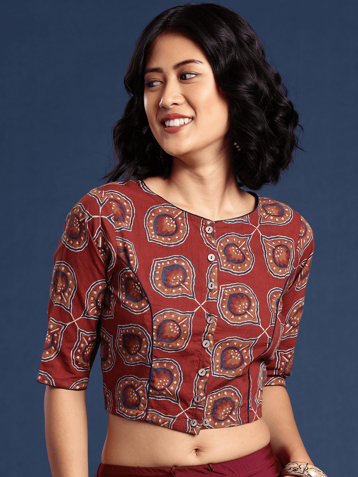 Woman wearing a patterned blouse against a dark blue background