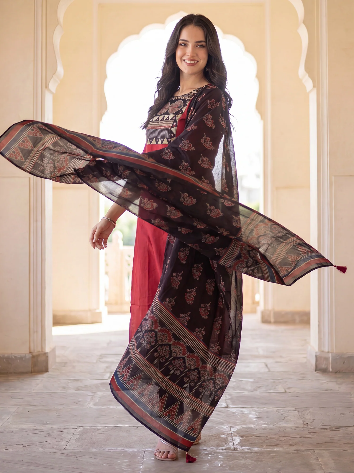 Woman holding a long, patterned scarf in an elegant setting