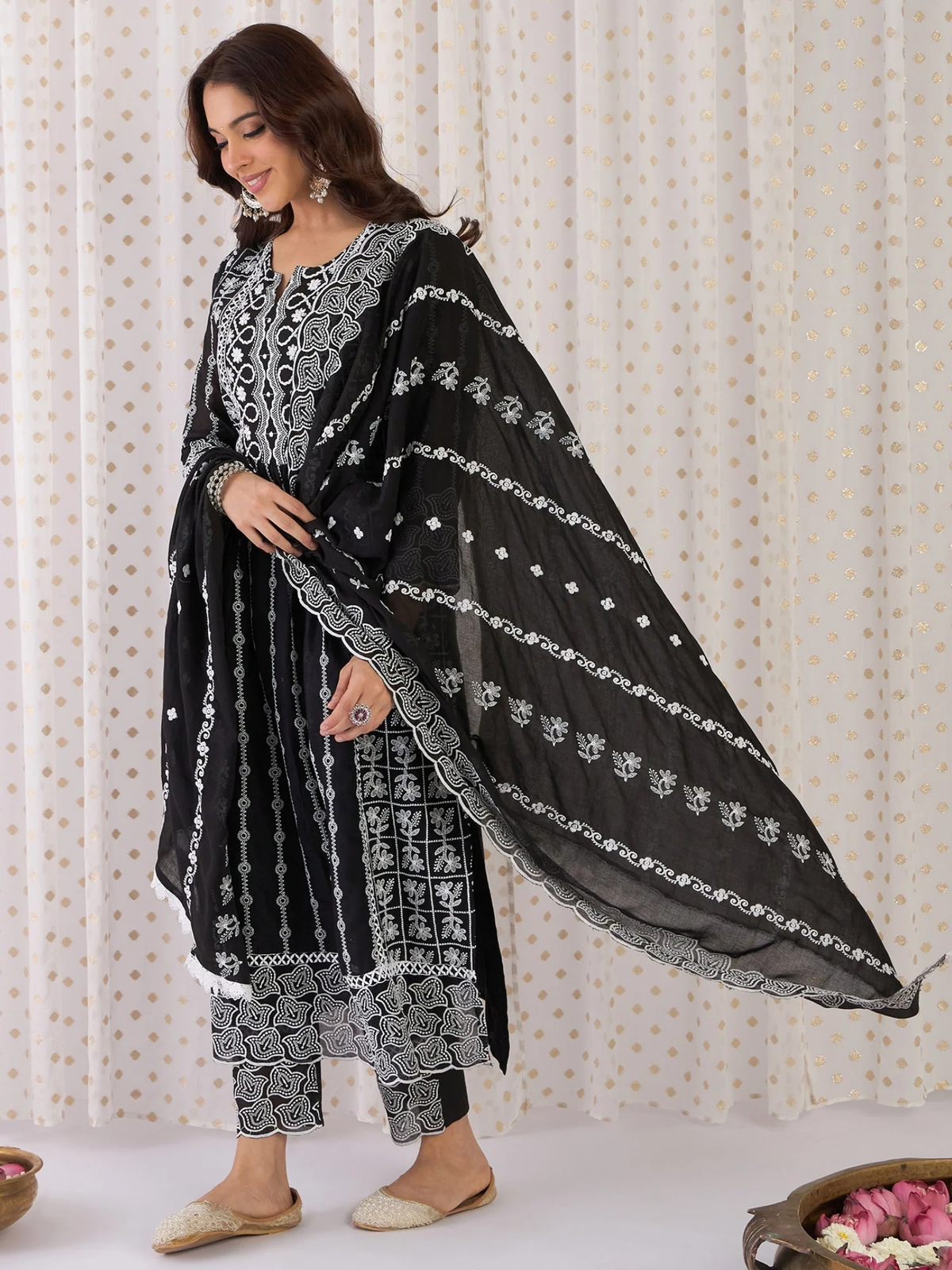 Woman wearing a black and white traditional outfit with a matching dupatta against a neutral background