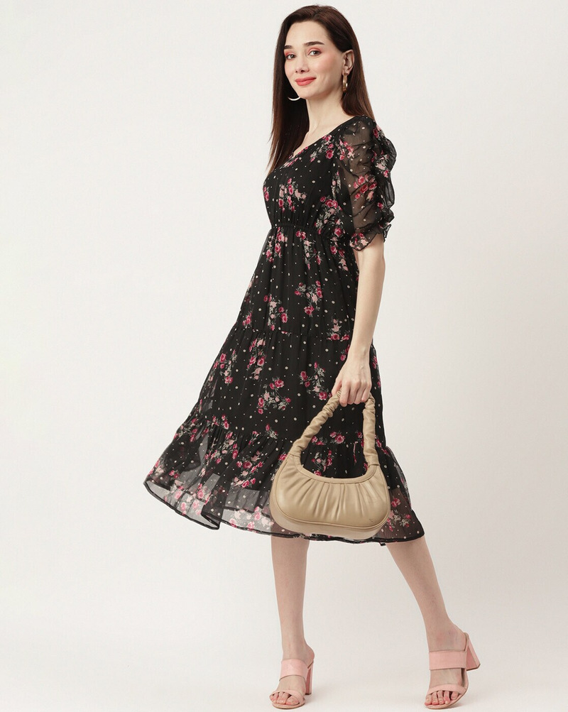 Woman wearing a black floral georgette wrap dress with puff sleeves and V-neck – lined fit & flare style for casual or party wear.