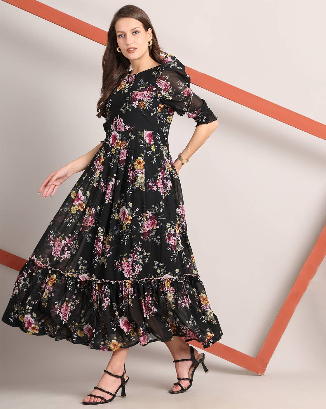 Woman wearing a handcrafted floral smocked tiered georgette dress with round neckline and stylised sleeves – playful and elegant casual wear.