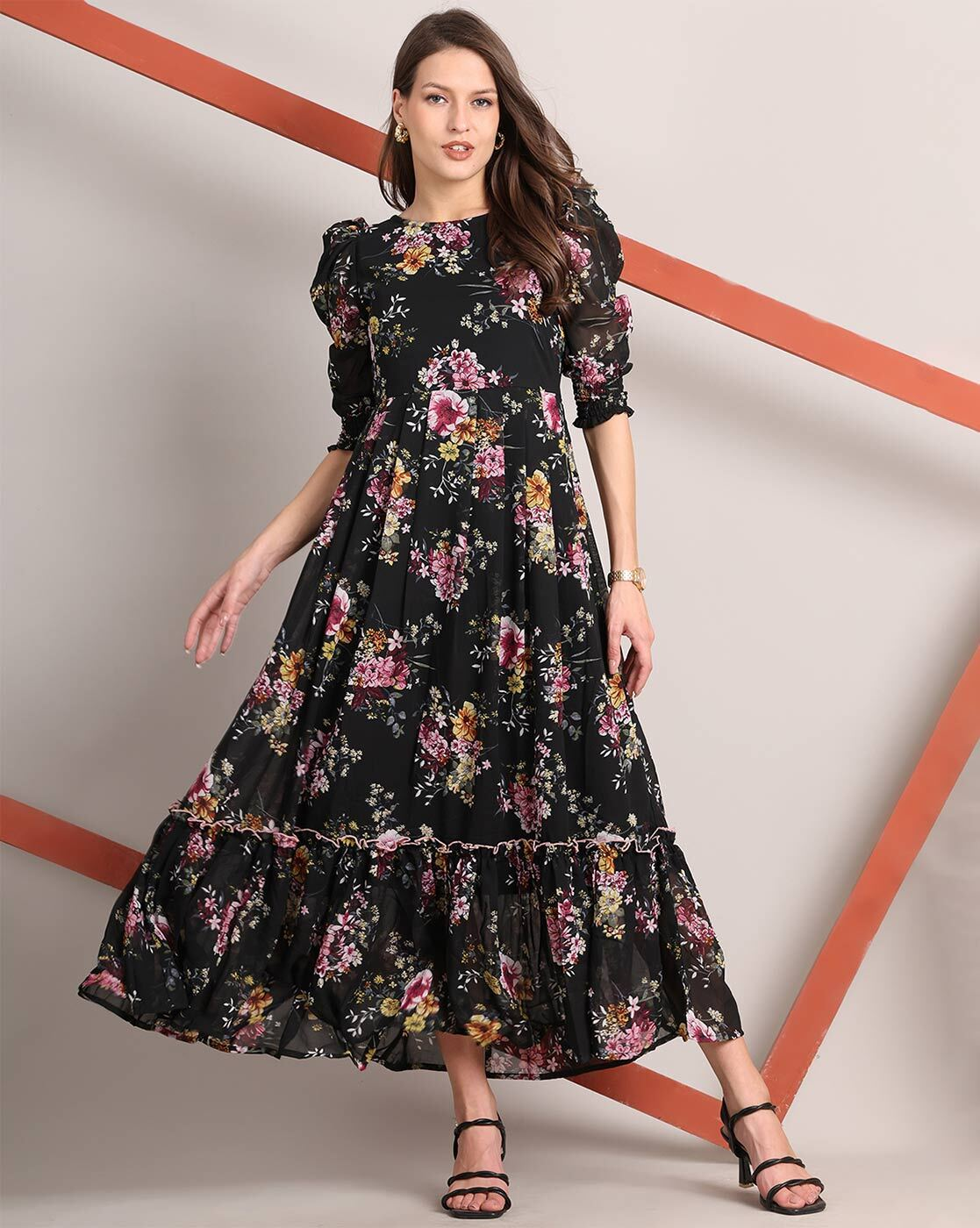 Woman wearing a handcrafted floral smocked tiered georgette dress with round neckline and stylised sleeves – playful and elegant casual wear.