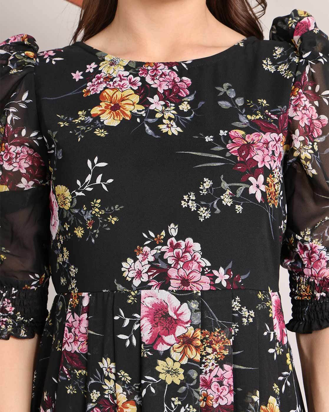 Woman wearing a handcrafted floral smocked tiered georgette dress with round neckline and stylised sleeves – playful and elegant casual wear.