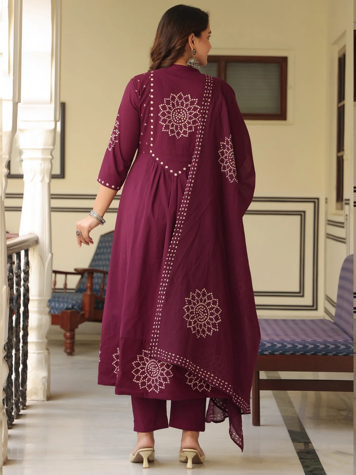 Woman wearing a maroon embroidered outfit in an indoor setting.