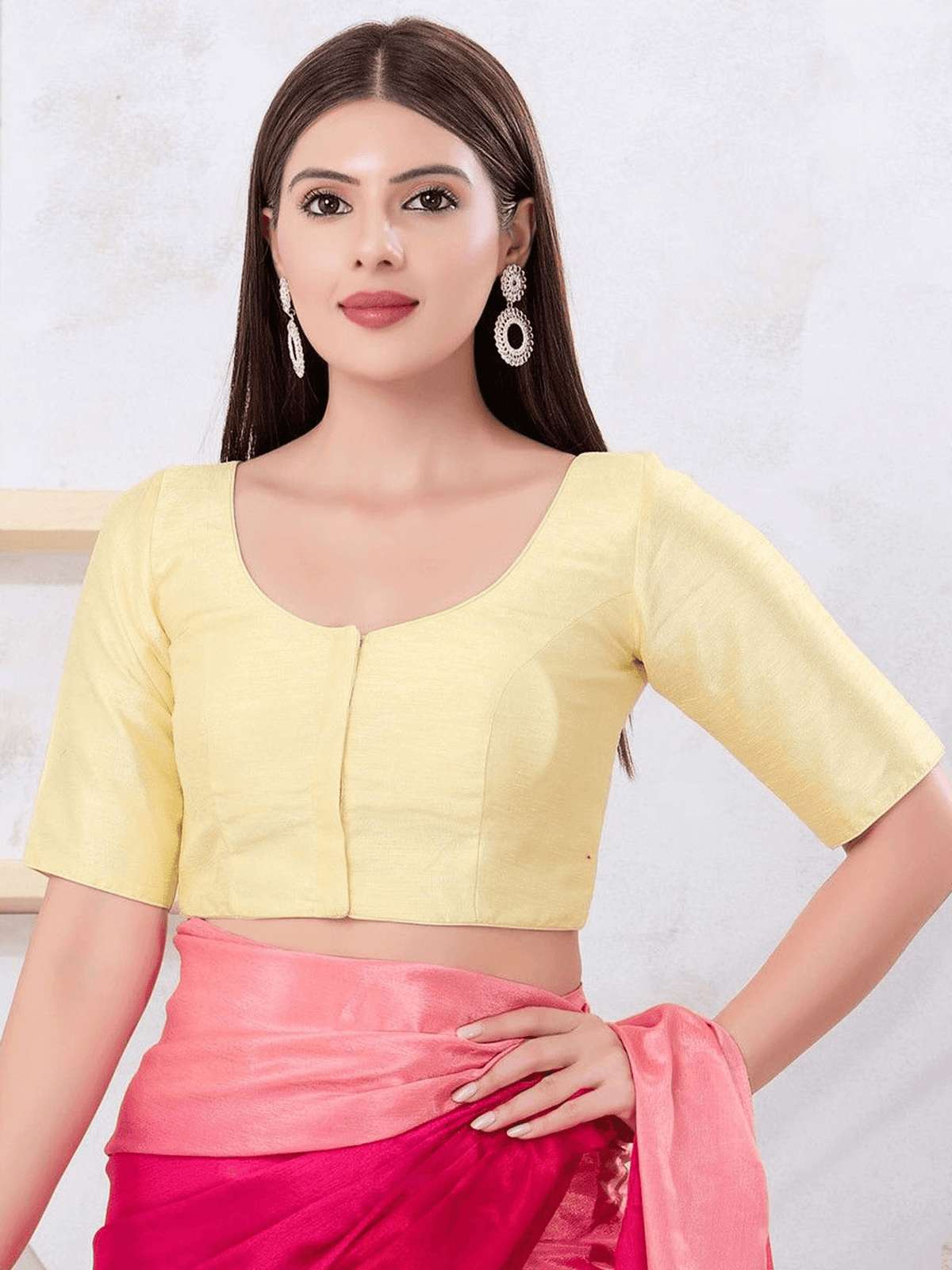 Woman wearing a yellow blouse and pink saree against a white background