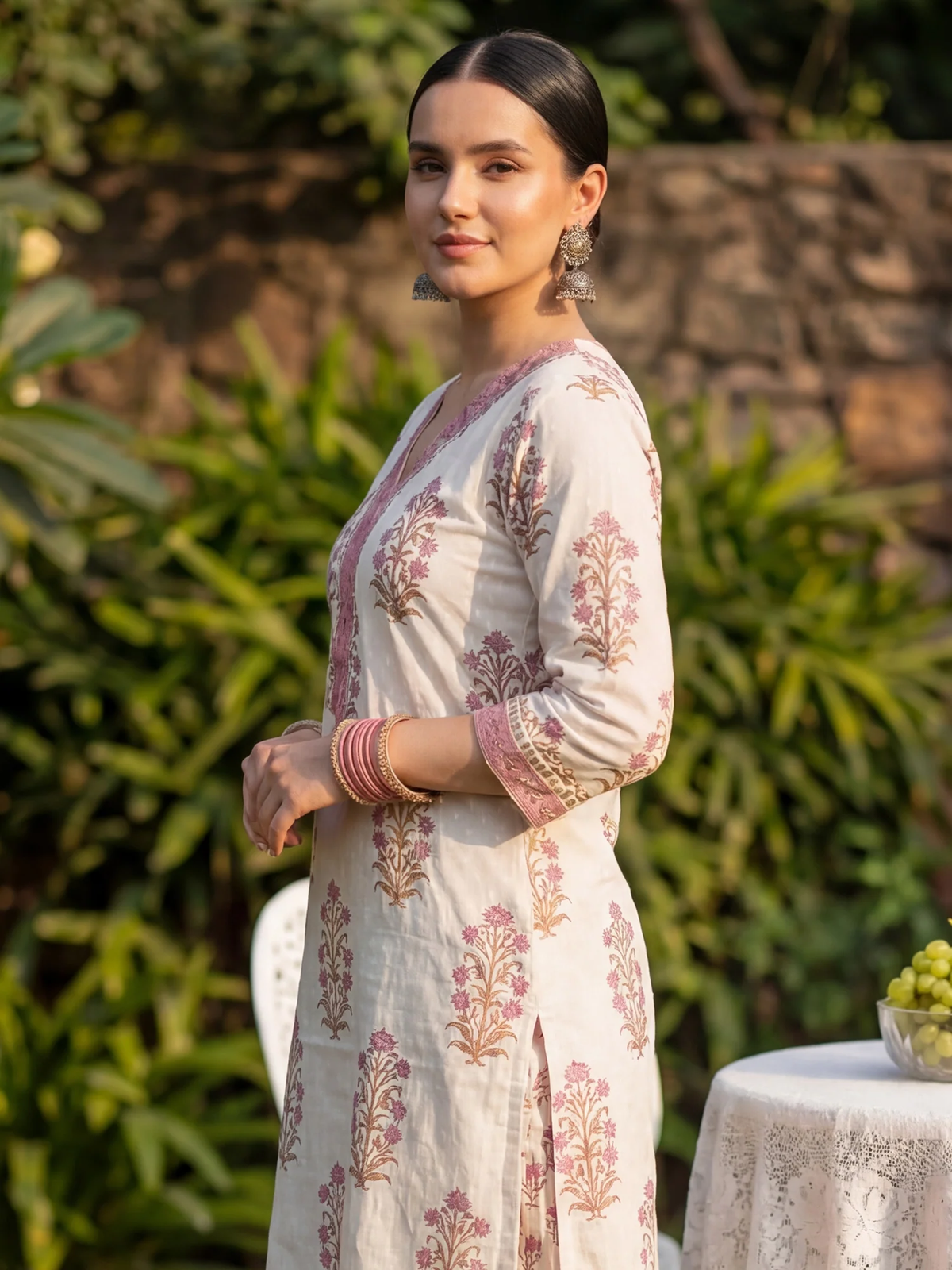 Woman in a floral dress standing outdoors with greenery in the background