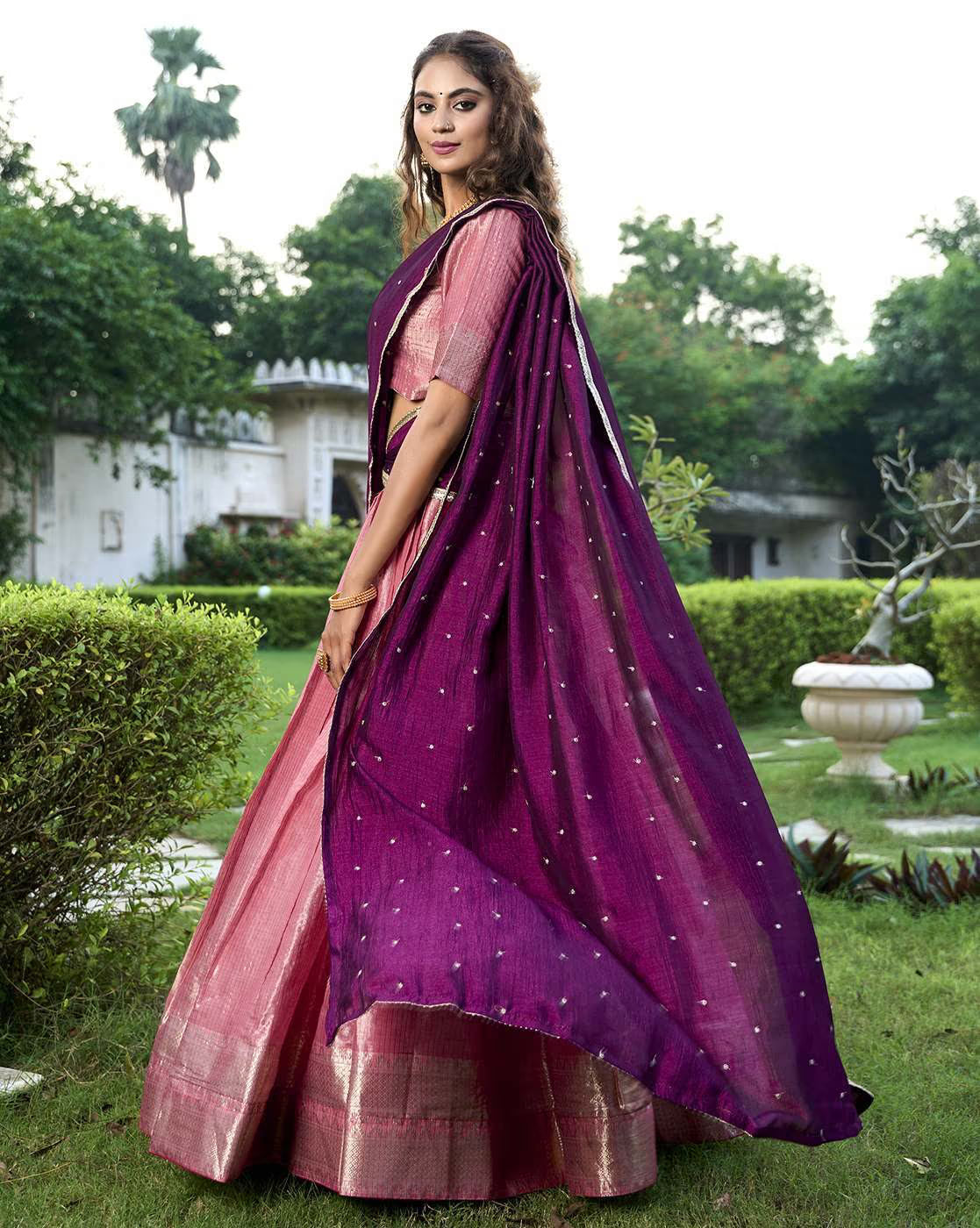 Model wearing AROMIE women's woven lehenga choli set with pink brocade skirt and purple dupatta