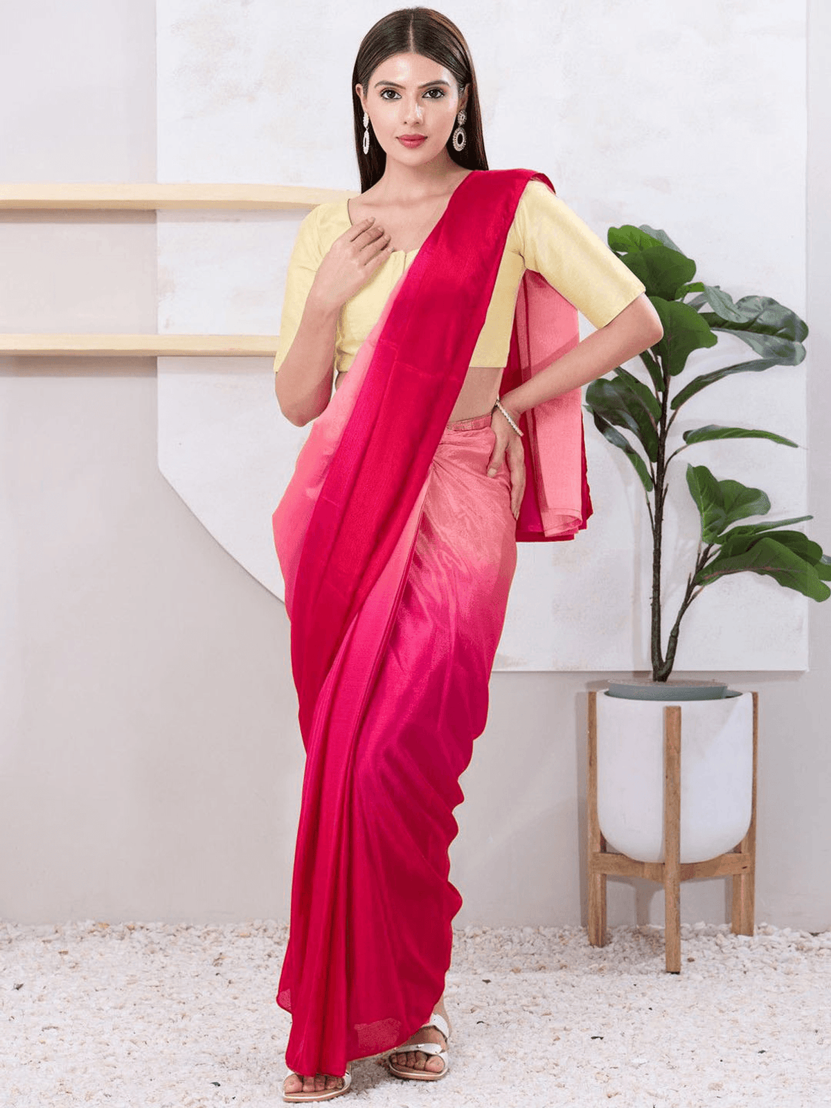 Woman wearing a pink saree with a yellow blouse in an indoor setting.