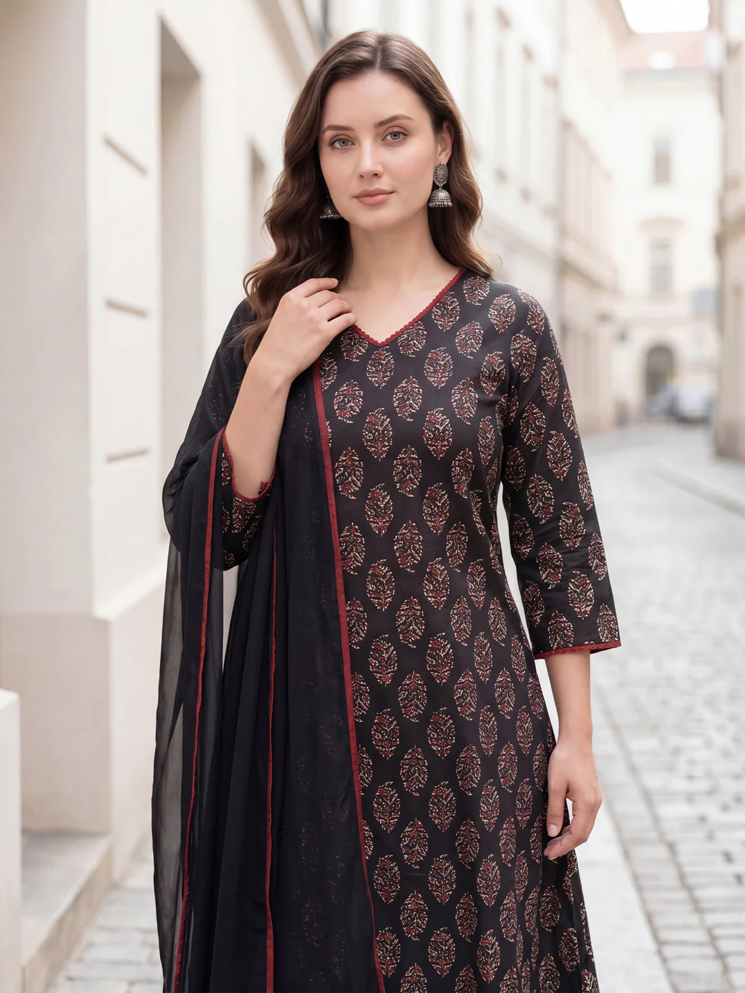Woman wearing a black and red patterned dress with a scarf in an urban setting
